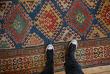 Intricate antique Kazak rug border, geometric pawn and floral motifs in red, blue, gold.