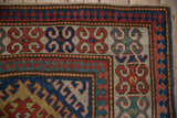 Antique Kazak rug corner: repeating floral blossom and reciprocating pawn borders in rich tones.