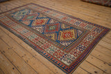 Antique Caucasian Kazak rug corner: floral blossom and pawn motif borders in madder red, sapphire blue.
