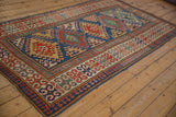 Antique Kazak rug corner: sapphire blue field with diamond motifs, madder red pawn border.