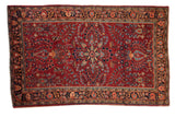 Vintage Sarouk rug with a starburst medallion and floral sprays on a burgundy red field.