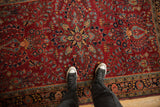 A perspective view of the vintage Sarouk's starburst medallion and dense cherry red floral field.