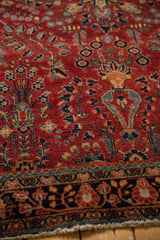 Detailed floral sprays and plant vases on the rich cherry red field of a vintage Persian Sarouk rug.