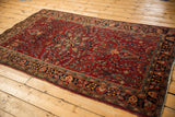 Angled view of a vintage Sarouk rug's intricate thousand flower design in cherry red and dark navy.