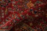Folded corner of a vintage Sarouk rug revealing its plush red pile and navy floral details.