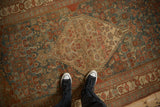 Distressed antique Persian Bijar rug detail with abrashed teal, red, and beige Herati design field.