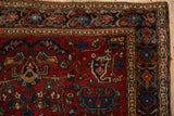 The ruby red boteh corner spandrel and sapphire blue vine border of an antique Farahan Sarouk rug.