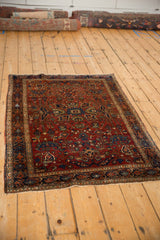 An antique Farahan Sarouk rug viewed from an angle, with a ruby red allover floral pattern.