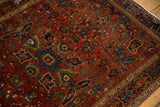 Angled view of an antique Farahan Sarouk's worn pile, with gem-toned floral and vine motifs.