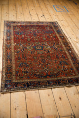 An antique Farahan Sarouk rug's allover floral pattern in gem tones, shown from a three-quarter perspective.