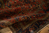 Folded corner of an antique Persian rug reveals a rich ruby pile and intricate sapphire blue border.