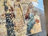 Angled detail of a mixed media collage with crinkled gold leaf, sheet music, and a figure.