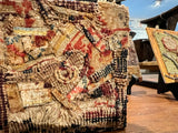 Angled view of the layered texture of antique silk and wool rug fragments.