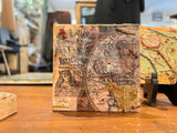 Angled view of Lillian Shad's art showing textured layers of vintage paper, netting, and thread.