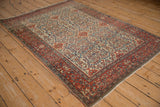 Angled view of an antique Farahan Sarouk rug, showing the elaborate allover field and palmette border.