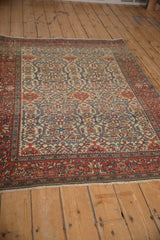 Angled view of an antique Farahan Sarouk rug, highlighting its ivory field and intricate palmette border.