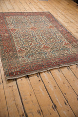 Angled perspective of an antique Farahan Sarouk rug, showcasing its dense allover pattern and palmette border.