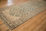 Angled view of a vintage Hamadan runner, showing its meandering vine border and distressed field.