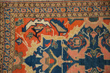 Senneh rug corner detail: indigo blue border, blush and saffron motifs, tangerine orange field.