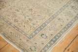 Distressed vintage Kaisary rug corner, ivory field with dusty blue and brown floral tendrils.
