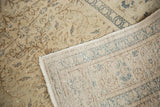 Distressed Kaisary carpet, showing faded ivory, blue florals, and its hand-knotted foundation.