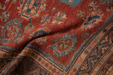A soft fold in an antique Caucasian Soumac carpet reveals its flat weave texture and floral motifs.