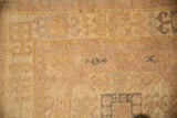 Worn hand-knotted pile of a vintage Oushak with faded geometric patterns in mauve, silver, and gold.