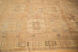 Angled shot of a distressed Oushak rug with faded mauve and silver geometric motifs.