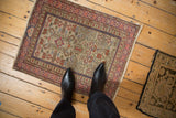 Vintage Shirvan rug with complex geometric motifs shown for scale on a wood floor.