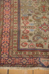 Corner detail of a vintage Shirvan rug with a rust and blue Kufic border and visible knot heads.