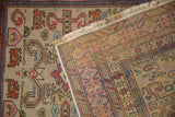 A folded corner of the vintage Caucasian rug displays the hand-knotted back and Kufic border.