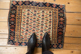 Antique Kurdish rug mat with geometric trellis pattern, viewed from above for scale.