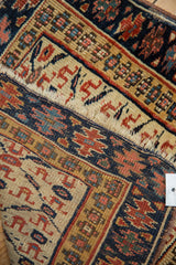 A close view of an antique Kurdish rug's end, showing the frayed edge and low, even pile.