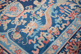 A beige dragon with blush and jade accents on a cobalt blue vintage Art Deco rug.