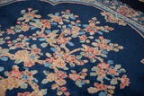 Angled detail of the Art Deco carpet's hand-knotted Tree of Life blooms on a dense cobalt blue pile.