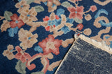 A folded corner of the vintage Art Deco carpet reveals its hand-knotted foundation.