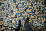 Worn pile of an antique Peking carpet showing blue scrolling vines and visible foundation.
