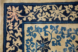 Scrolling vines in navy, cobalt, and blush on the worn corner of an antique Peking rug.