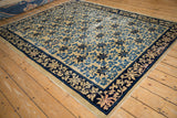 Angled perspective of the antique Peking carpet's blue scrolling vine pattern on an ivory field.