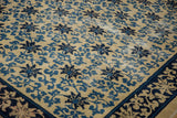 Detail of the worn, hand-knotted texture and blue scrolling vine design of a Peking rug.
