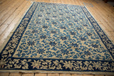 Angled view of an antique Peking carpet showing its low pile and blue vine pattern.