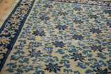 Storied wear on an antique Peking carpet, revealing the foundation beneath cobalt blue vine motifs.