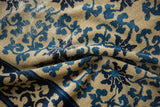Wear across the cobalt blue scrolling vine motif revealing the carpet's woven foundation.