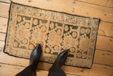 A person's view of a distressed Kars rug fragment with a faded geometric pattern.