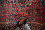 Intricate sapphire blue floral sprays on the lustrous raspberry red pile of an antique Sarouk carpet.