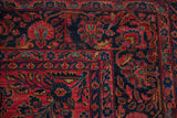 Corner detail of a Sarouk carpet with a navy blue palmette and meandering vine border.