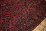 Detailed angle on the palmette and vine border of an antique Sarouk's raspberry red field.