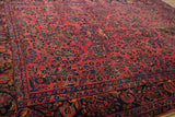 Angled view of the allover floral sprays and low pile on a raspberry red antique Sarouk carpet.