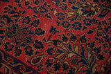 Texture detail of an antique Sarouk carpet showing floral sprays and visible white knots.