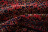 Softly folded antique Sarouk showing the dense pile and floral knots in raspberry red and navy.